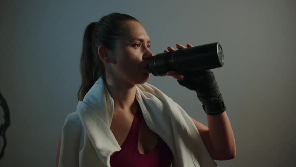 A Young Athletic Woman Drinks Water From a Bottle After a Workout alt