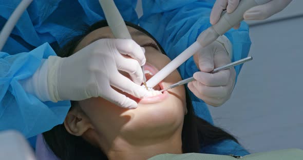 Dentist treating teeth to woman patient in clinic alt