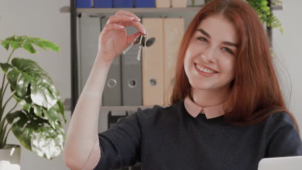 Real estate. Overjoyed red hair female student showing keys from new apartment. Happy hindu female h