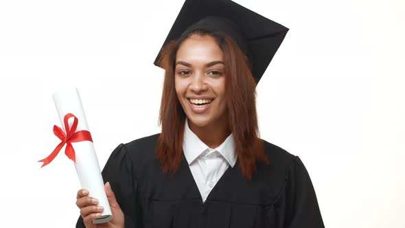Smiling Attractive Female African American Graduate in Academic Dress Holding Her Diploma and alt