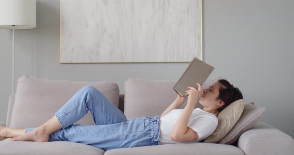 Sleepy Woman Reading Paper Book Relaxing at Home After Hard Work
