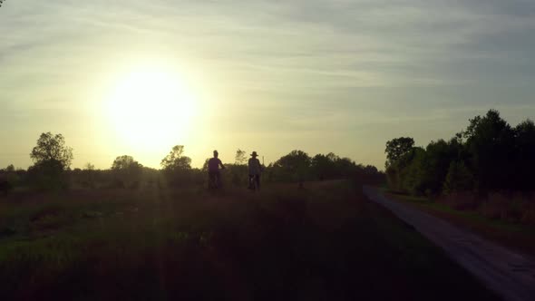 Two Women Ride Bicycles in the Park alt