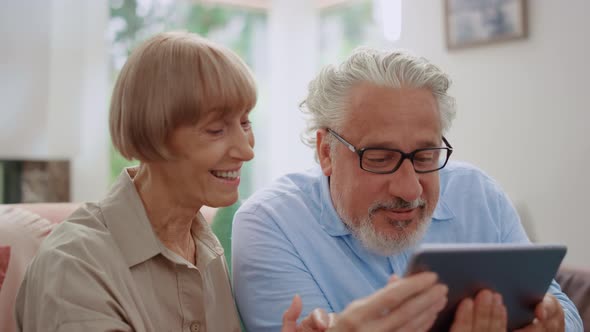 Grandmother and Grandfather Talking By Video Call on Tablet with Grandchildren alt