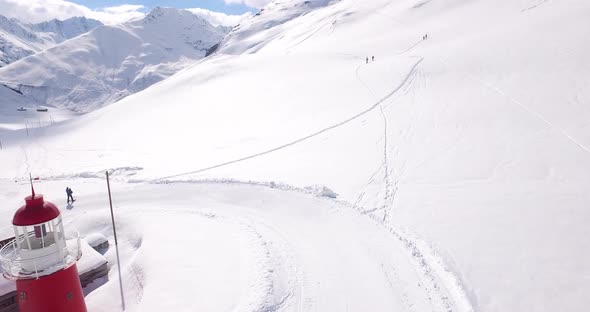 Aerial establishing shot of people walking up snowy mountain in the alps alt