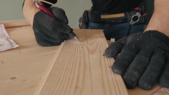 A Gloved Construction Worker Writes on a Blackboard with a Red Pencil