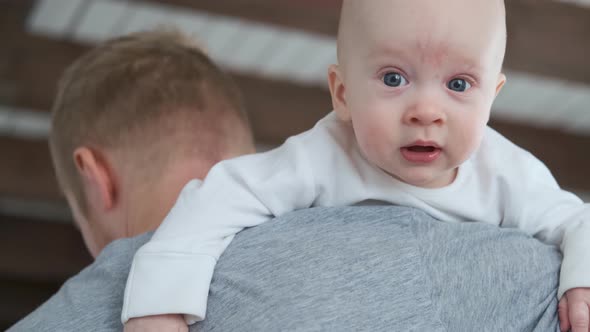 portrait of a surprised baby on dad’s shoulder