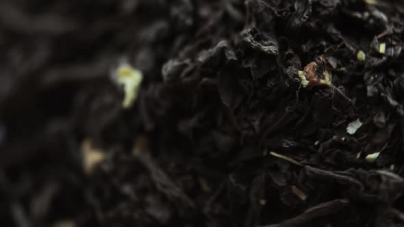 Rotating Pile of Dried Black Largeleaves Herbal Tea with Fruits Closeup View