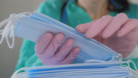 A Woman in Pink Gloves Counts Medical Disposable Masks Closeup
