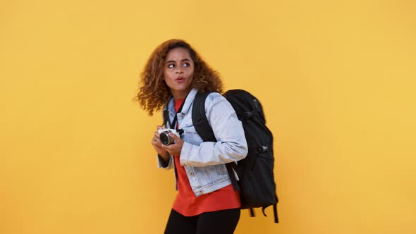 Solo woman tourist taking photo with camera in yellow isolated studio background