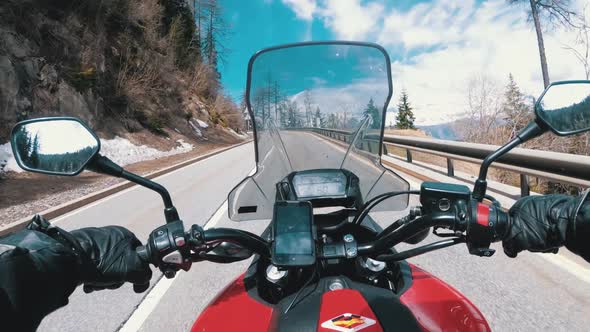 Motorcyclist Rides on Beautiful Landscape Mountain Road Near Snowy Switzerland Alps