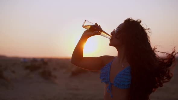Young Hispanic Woman with Curly Hair Drinking Beer at Beach