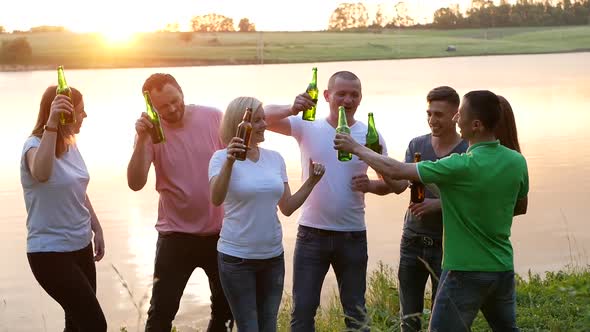 Happy Friends Dancing at Sunset with a Drink in Their Hands alt