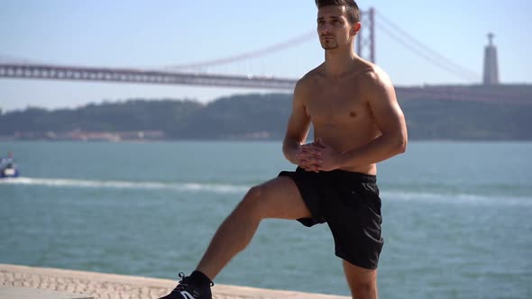 Focused Bare-chested Sportsman Exercising Near River alt