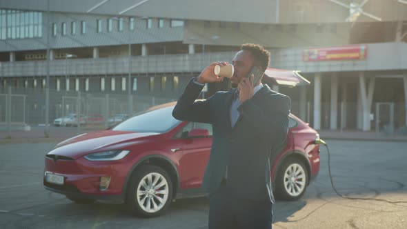 African American Businessman Talking on Mobile Phone and Drinking Coffee While alt
