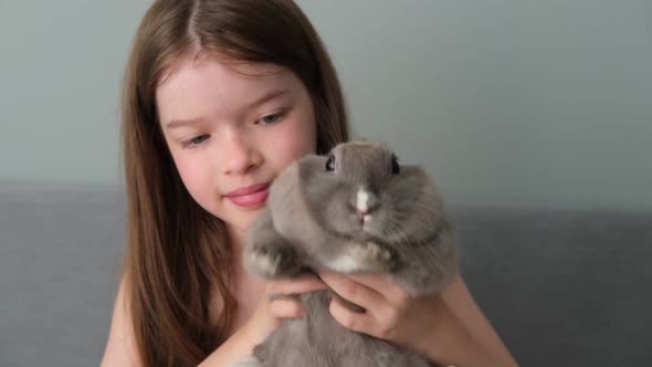 a Little Girl Holds a Pet Rabbit in Her Arms and Plays with It