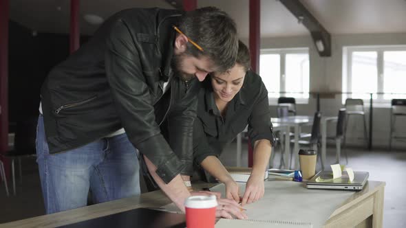 Young Man and Woman Working on a Project Drawing and Thinking in Modern Office alt