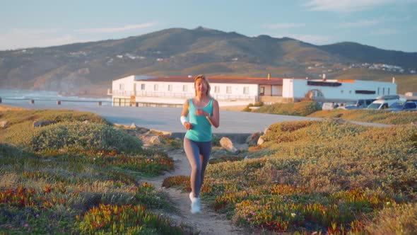 Runner Woman Running in the Sunny Path Road Near Ocean alt
