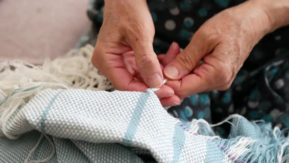 Creating a fringe on a woven shawl. Hands of artisan at work