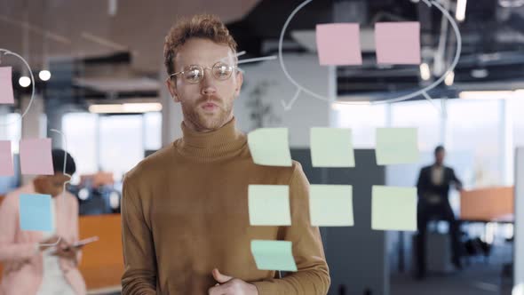Serious Businessman Manager Examining Information on Sticky Notes and Finding Solution alt