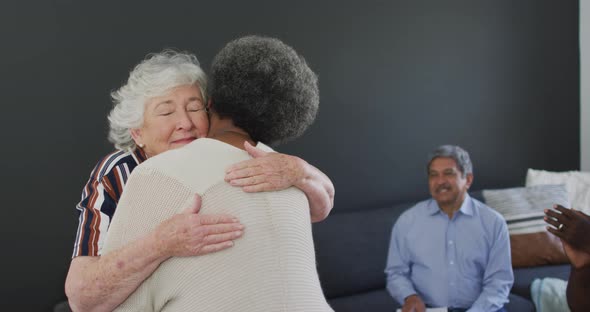 Caucasian senior woman giving support to african american female friend on meeting alt