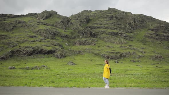 Woman Hitchhiker Is on Asphalt Road Trying To Vote Stop the Car with Thumb Up. alt