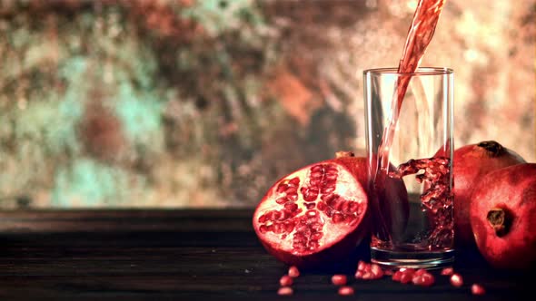 Super Slow Motion is a Jet of Pomegranate Juice Pouring Into the Glass on the Table alt