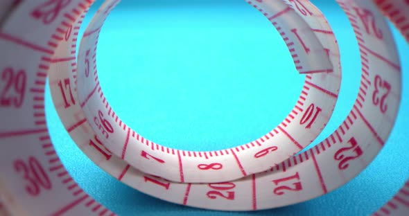 Super Macro Shot of a Measuring Tape Into a Roll of Sewing and Colored Thread on the Background Blue alt