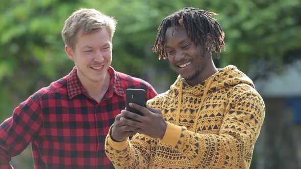 Young Multi-ethnic Friends Using Phone Together in the Streets Outdoors alt