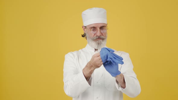 Man in Medical Hat Put on Disposable Gloves on Copy Space alt