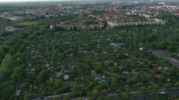 Fly Above Community Gardens Surrounded By Railway Tracks and Rows of Residential Buildings alt