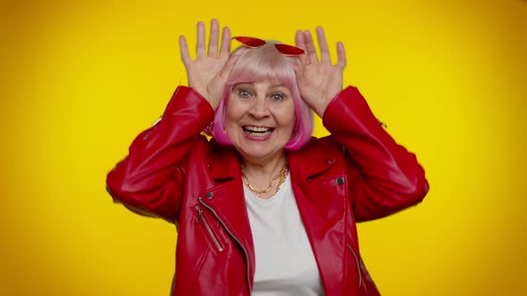 Funny Silly Senior Old Granny Woman Smiling Friendly and Doing Bunny Ears Gesture on Head Fooling alt