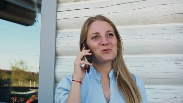Beautiful Blonde Woman Joyfully with a Smile Talking on a Smartphone alt