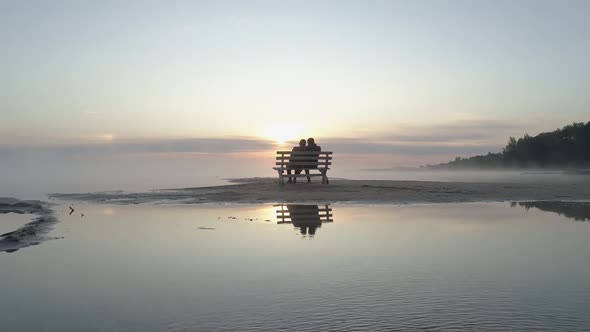 Couple in Love Sitting on a Bench in the Middle of the Lake and Meet the Sunrise alt