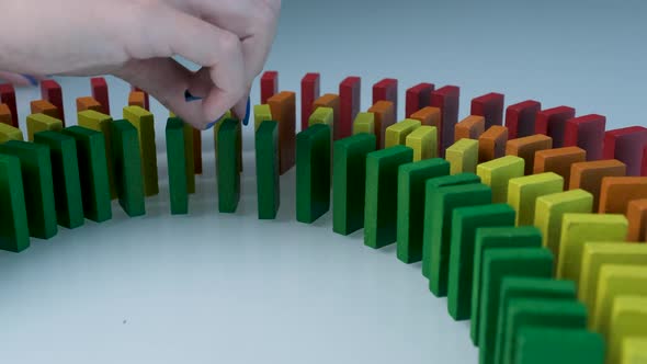 Line up of Dominoes in Rainbow Falling Colors with LGBT Colors of a Hand alt