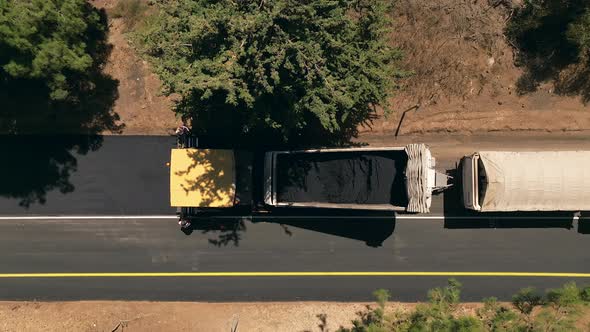 Asphalt paving machine escorted by an Asphalt truck at work, Top down aerial view. alt