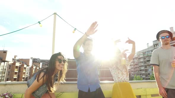 Four cheerful friends dancing on the rooftop terrace alt