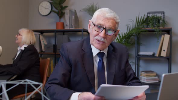 Senior Business Company Manager Sitting at Office Desk Reading Resume Successful Job Interview alt