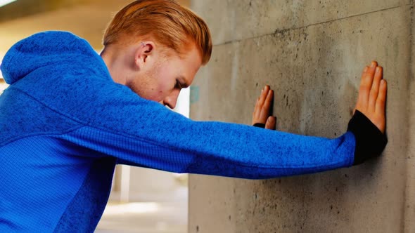 Young man pushing against wall while exercising, 4K 4k alt