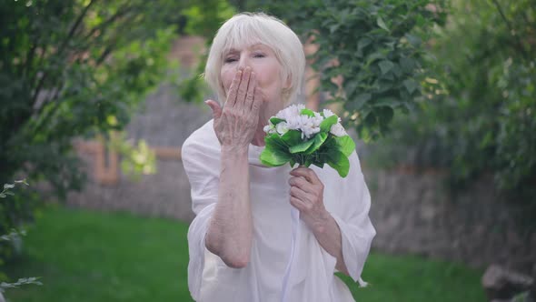 Front View Portrait Confident Proud Senior Bride in Wedding Dress Gesturing Air Kiss Looking at alt