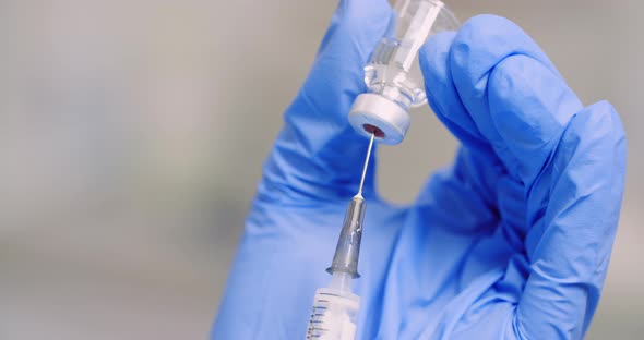 Extreme Close Up of Hand Holding Syringe and Vaccine in Hand in Laboratory. alt