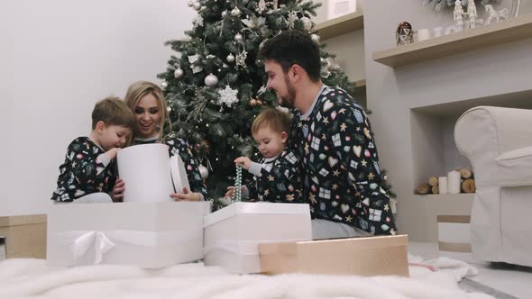 Family of Four Unwrapping Christmas Gifts Near Christmas Tree alt