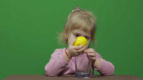 Beautiful Young Girl Squeezes Lemon Juice with a Grimace on Her Face alt