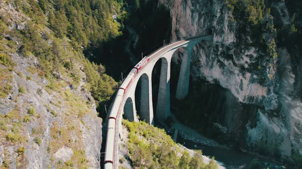 Aerial View of a Moving Red Train Along the Landwasser Viaduct in Swiss Alps alt