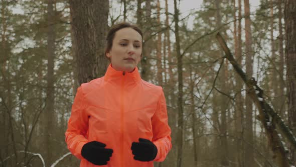 Female runs in park. Young confident woman jogging in forest in offseason. alt