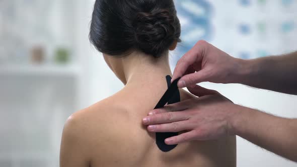 Doctor Applying Y-Shaped Tapes on Patient Upper Back, Alternative Medicine alt