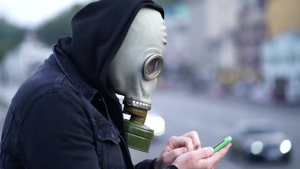 Man with respirator using smartphone.