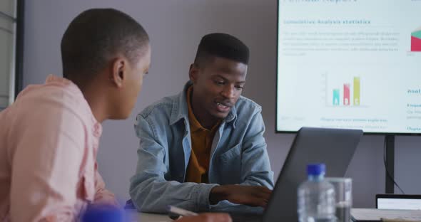 Serious african american male and female colleague in discussion at meeting using laptop and screen alt