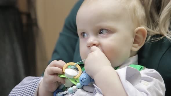 Baby sucks a white nipple lying in his round bed alt