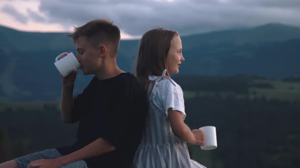 Siblings Enjoying Hot Drink in Mountains alt