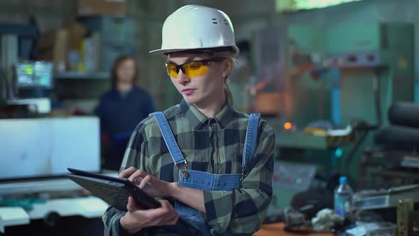 A Female Engineermanager in a Protective Helmet Inspects the Plant with a Digital Tablet